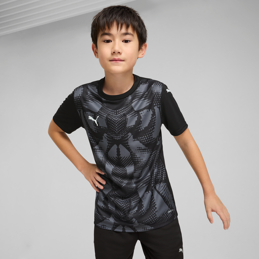 A child wearing a black Puma sports jersey with a geometric pattern.