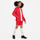 Nike Dri FIT Academy 23 Woven Track Jacket in University Red/Gym Red with red nike shorts and white nike socks and black nike football boots